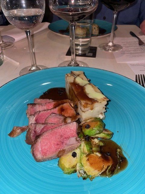 A blue plate with meat and vegetables on it