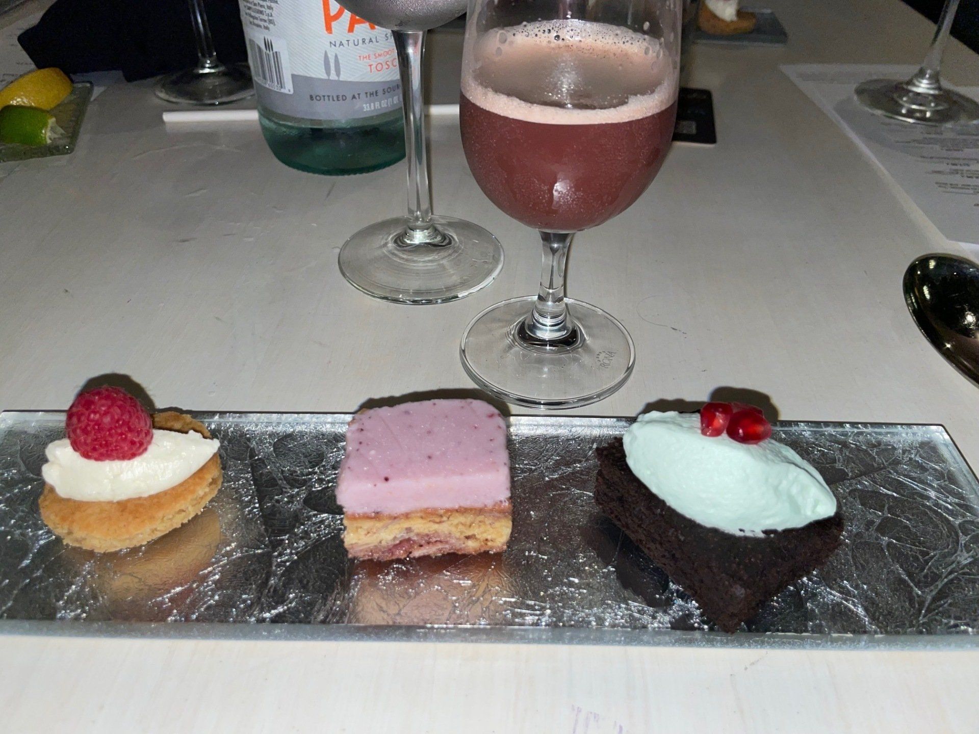 A plate of desserts and a glass of wine on a table
