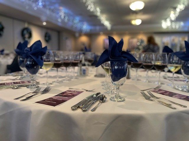 A table set for a wedding reception with wine glasses and napkins on it.