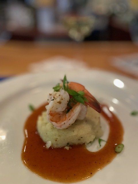 A close up of a plate of food with shrimp and mashed potatoes