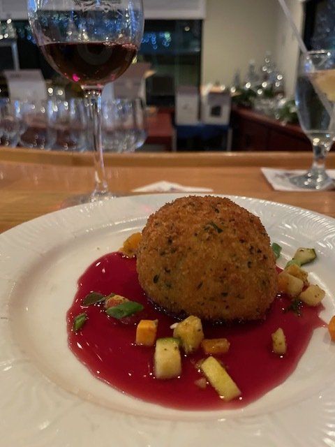 A plate of food with a glass of wine in the background