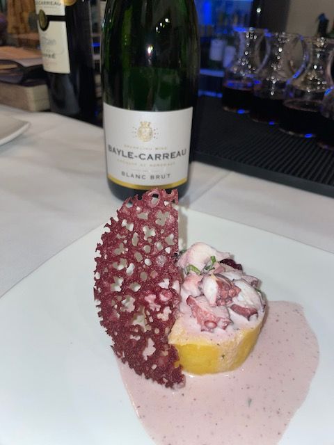 A bottle of rayle carreau wine next to a plate of food