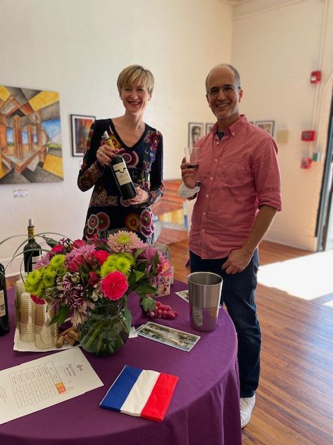 A man and a woman standing next to a table holding wine bottles