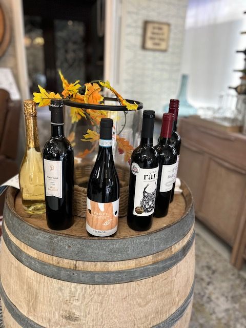 Several bottles of wine are sitting on top of a wooden barrel.