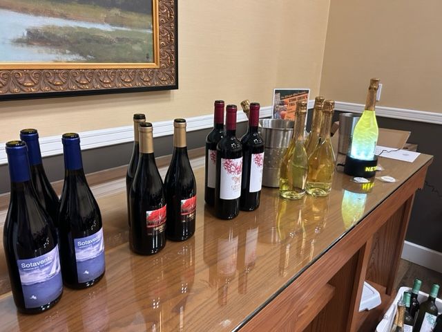 Bottles of wine are lined up on a glass table.
