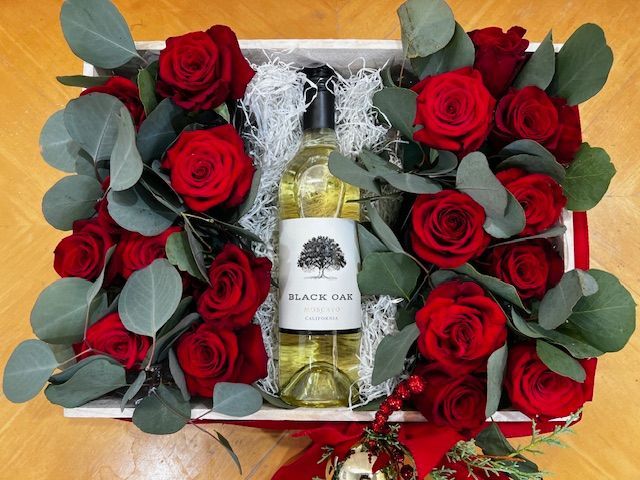 A box filled with red roses and a bottle of wine