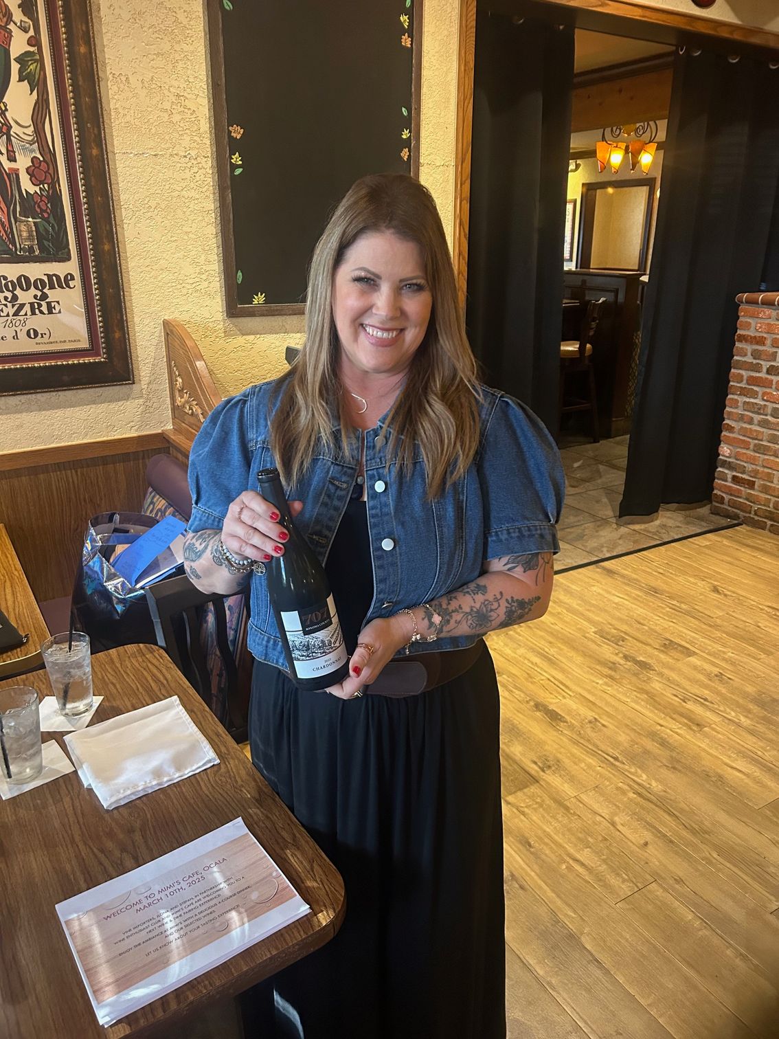 A woman is holding a bottle of wine in a restaurant.