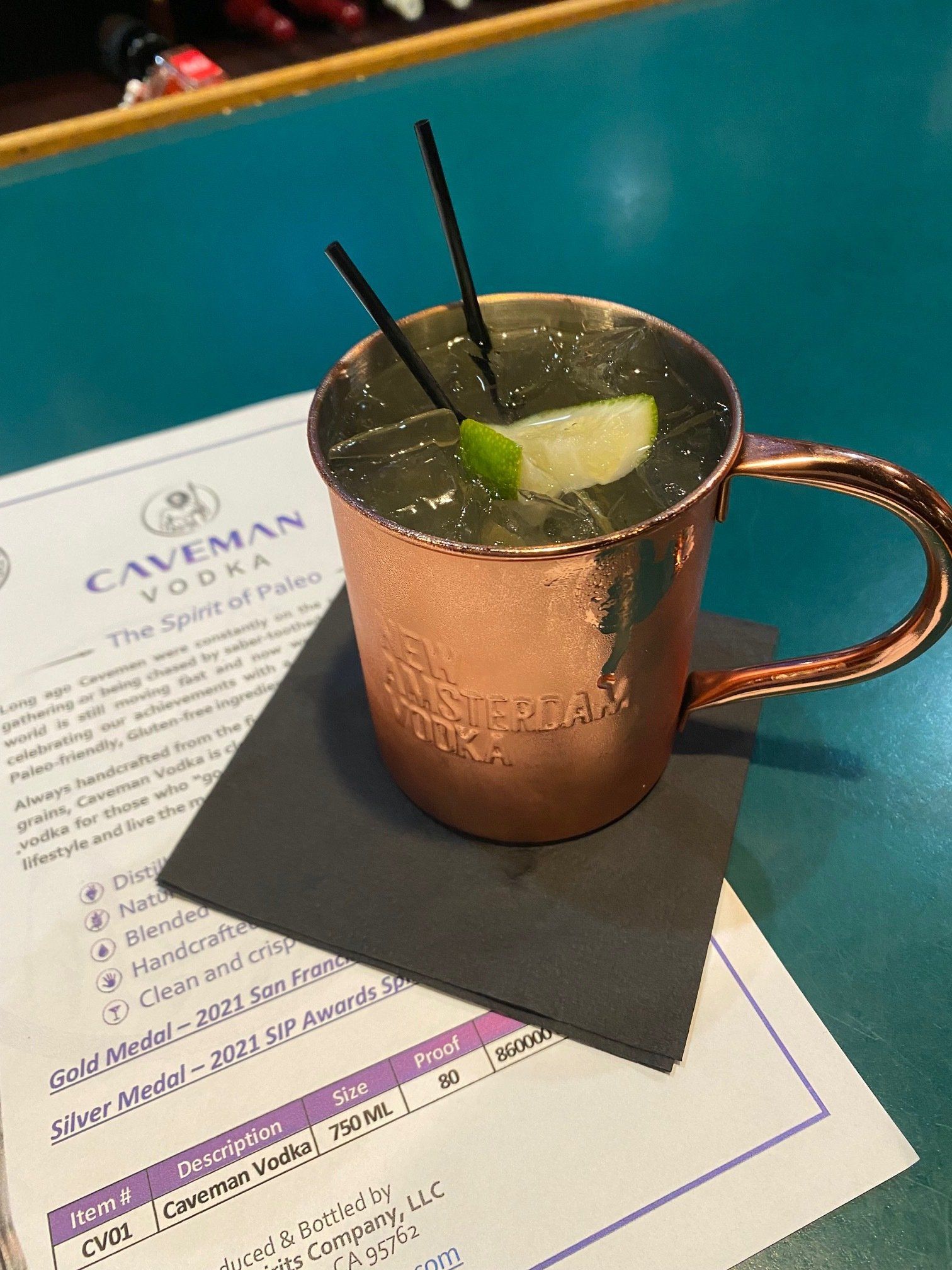 A copper mug with a drink in it is on a napkin on a table.