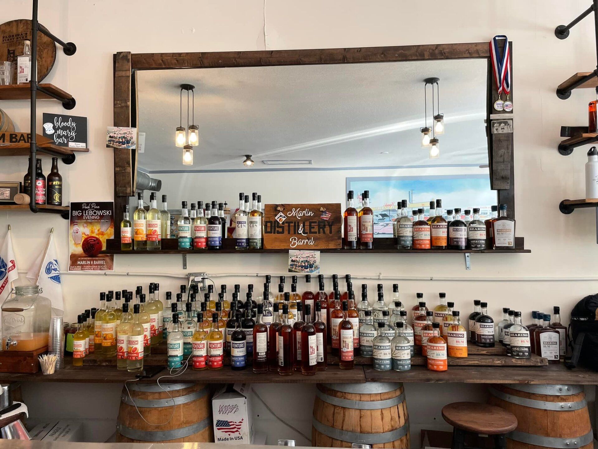 A bar filled with lots of bottles and barrels and a large mirror.