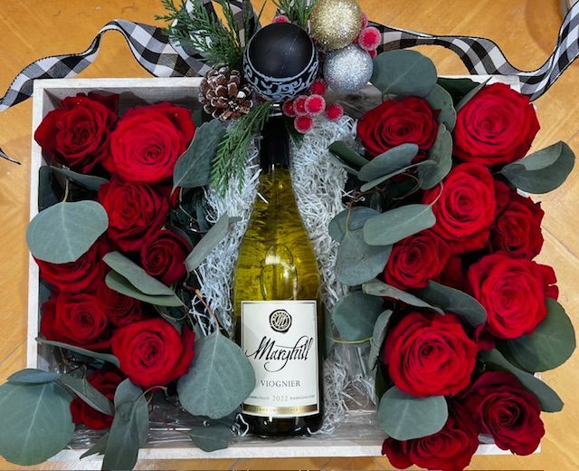 A box filled with red roses and a bottle of wine