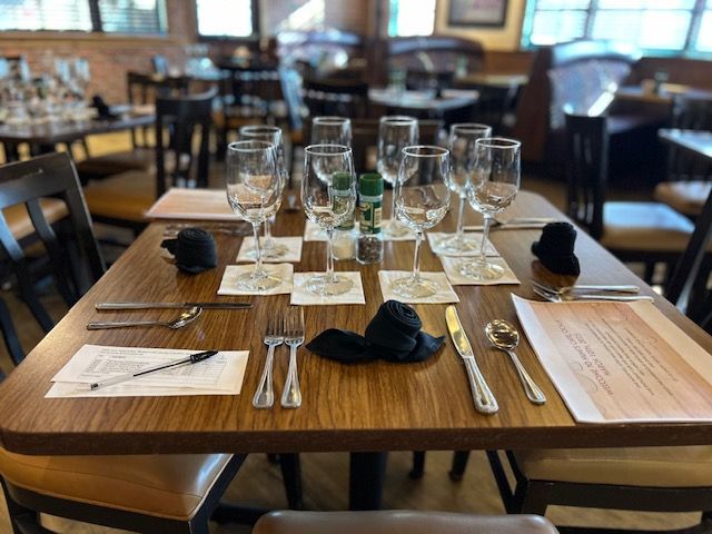 A wooden table with wine glasses and silverware on it
