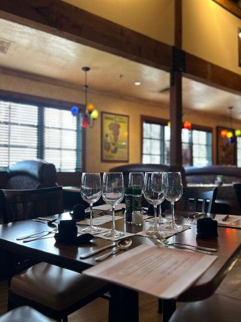 A restaurant with a table set with wine glasses and a menu