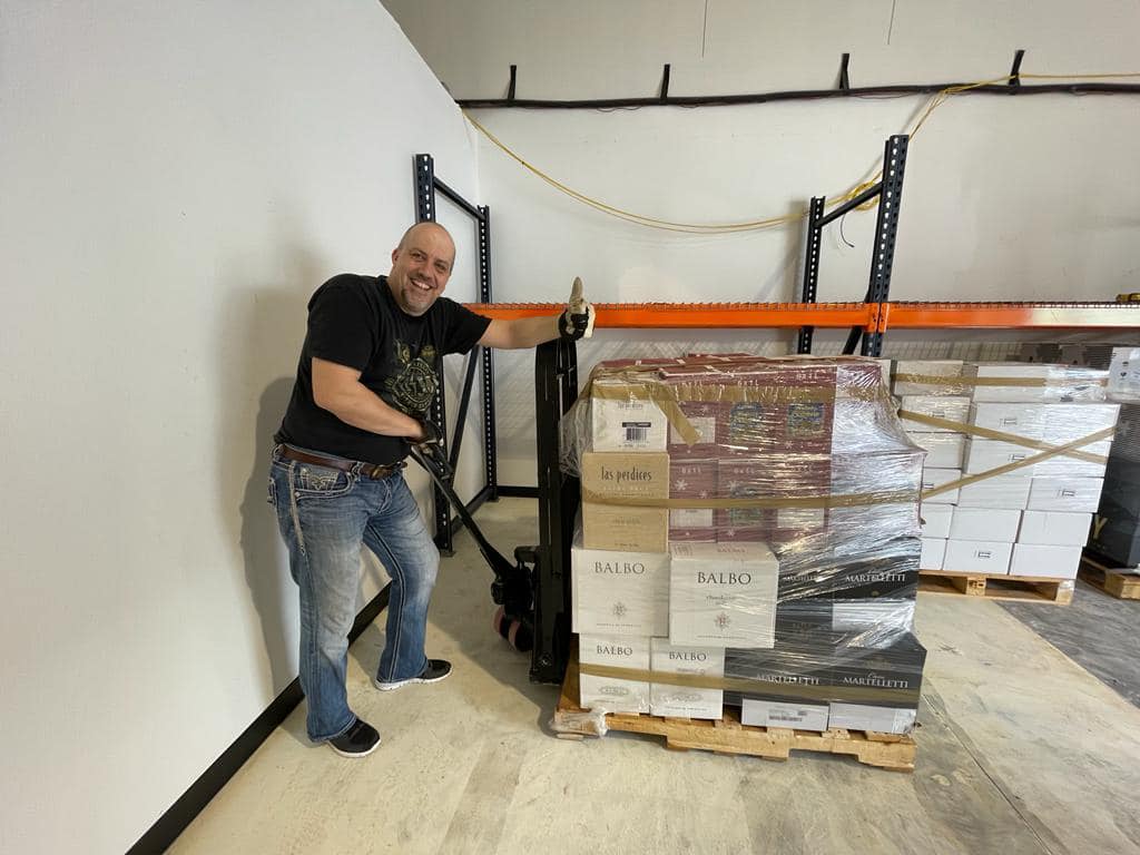A man is pushing a pallet with boxes on it in a warehouse.