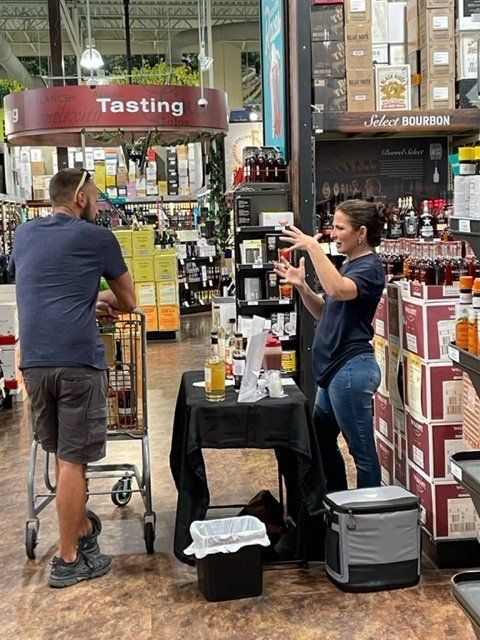 A man and woman are standing in front of a sign that says tasting