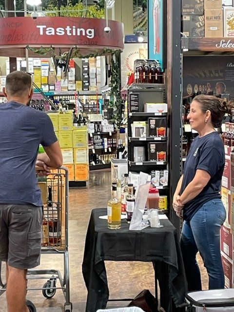 A man and a woman are standing in front of a sign that says tasting