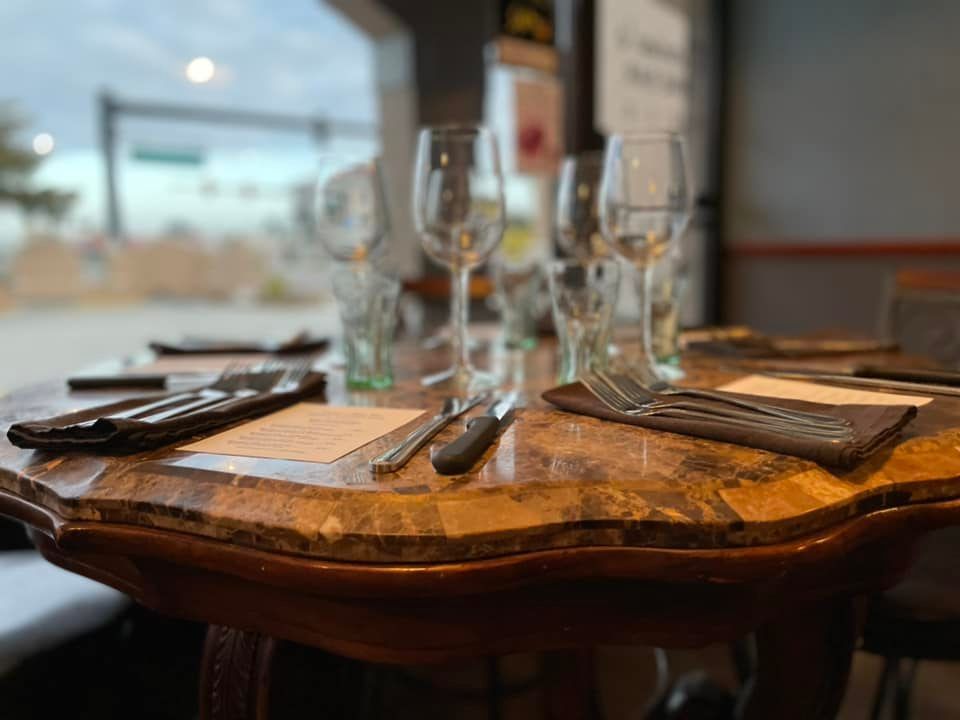 A table in a restaurant with wine glasses and silverware on it.
