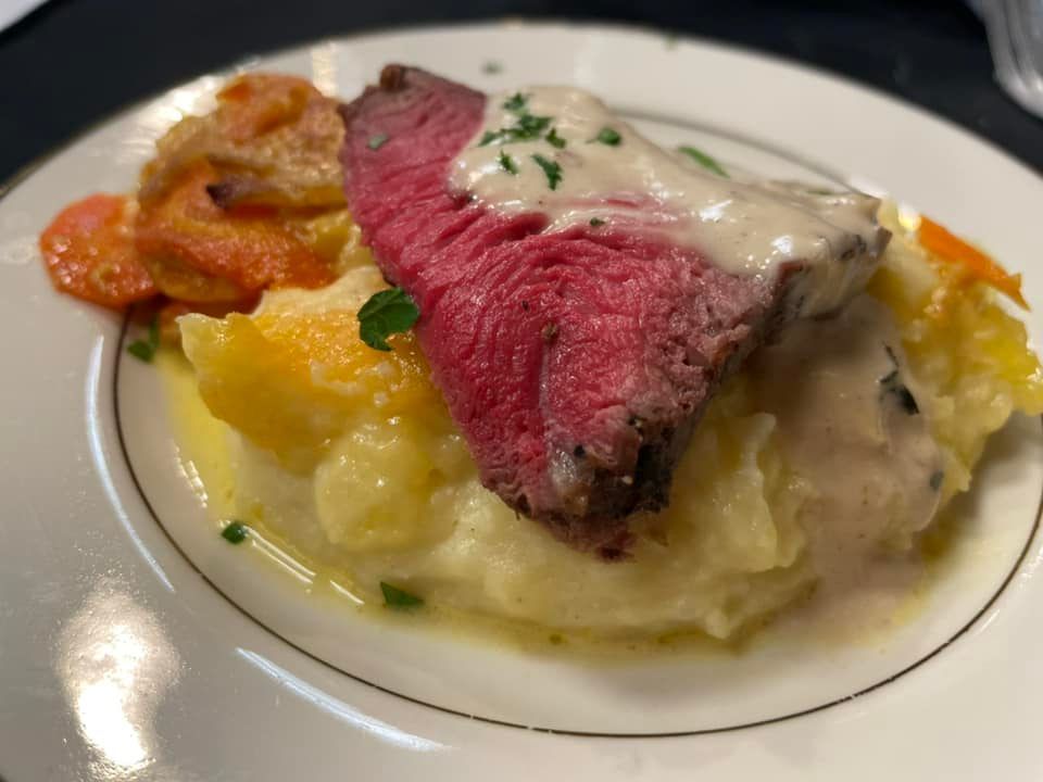 A white plate topped with mashed potatoes , meat and vegetables.