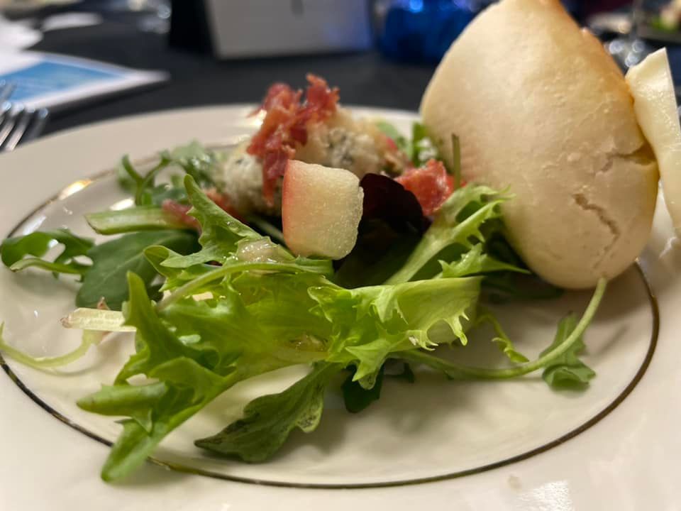 A white plate topped with a salad and a bread roll.