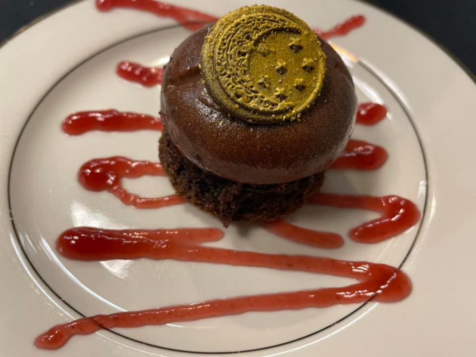A white plate topped with a chocolate dessert and strawberry sauce