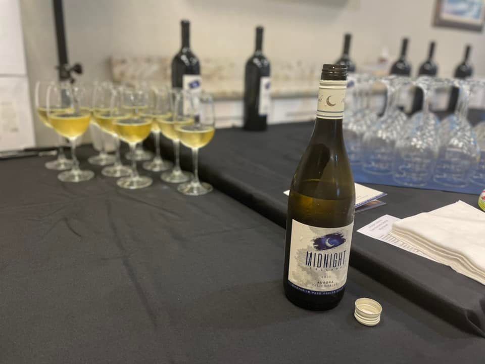A bottle of wine is sitting on a table next to a row of wine glasses.