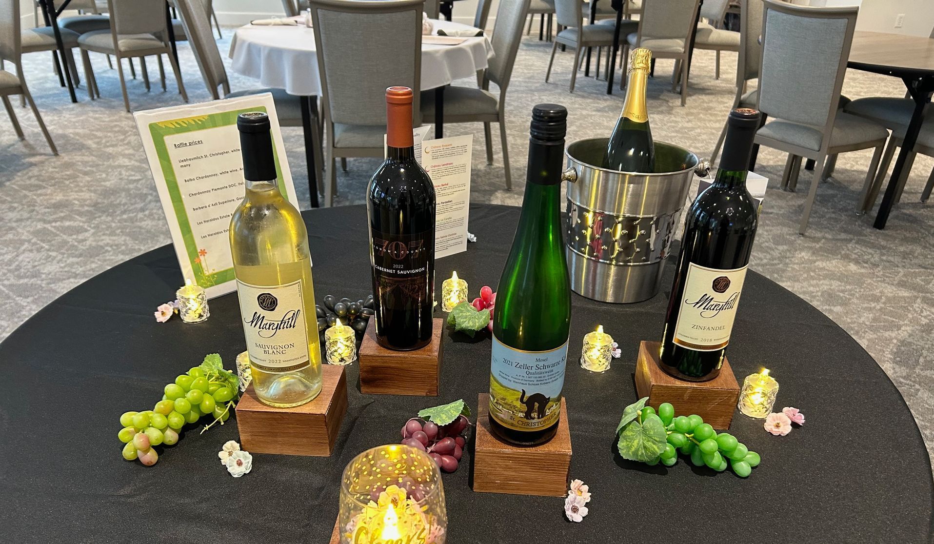 A table with bottles of wine and grapes on it.