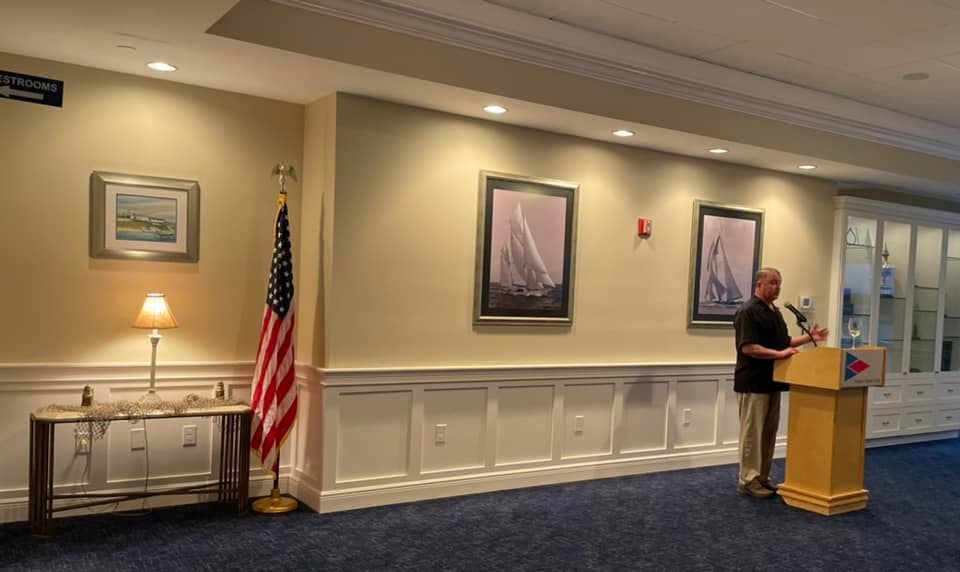 A man is standing at a podium in front of an american flag.