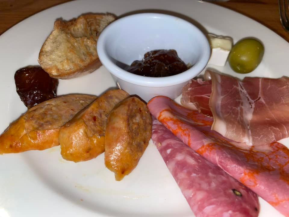 A white plate topped with a variety of meats and cheeses