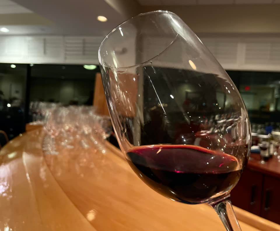 A glass of red wine is sitting on a wooden table