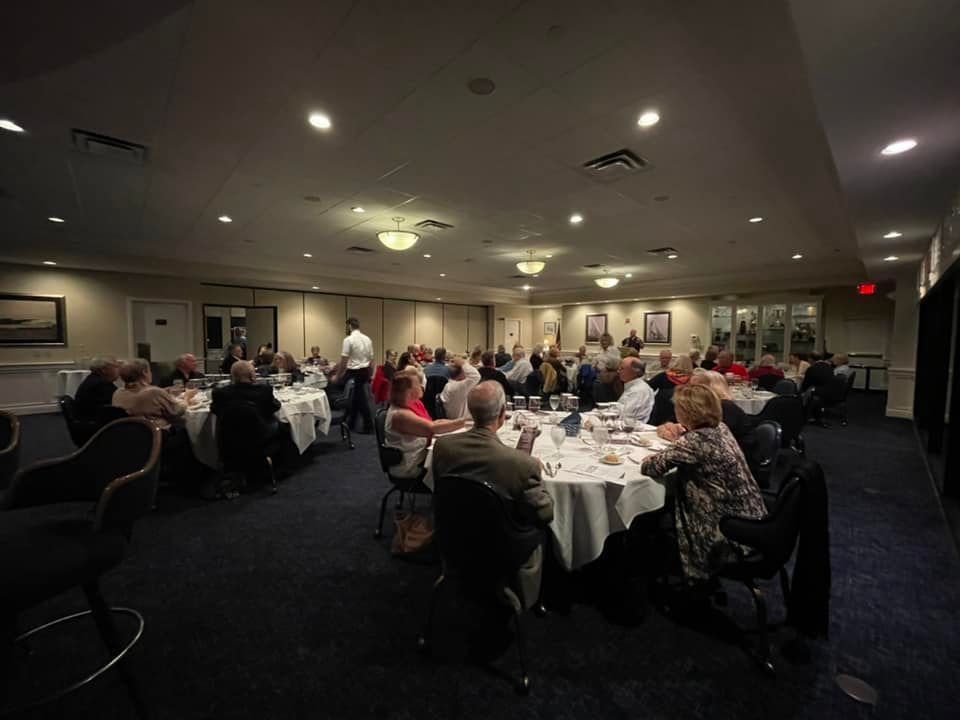 A group of people are sitting at tables in a large room.