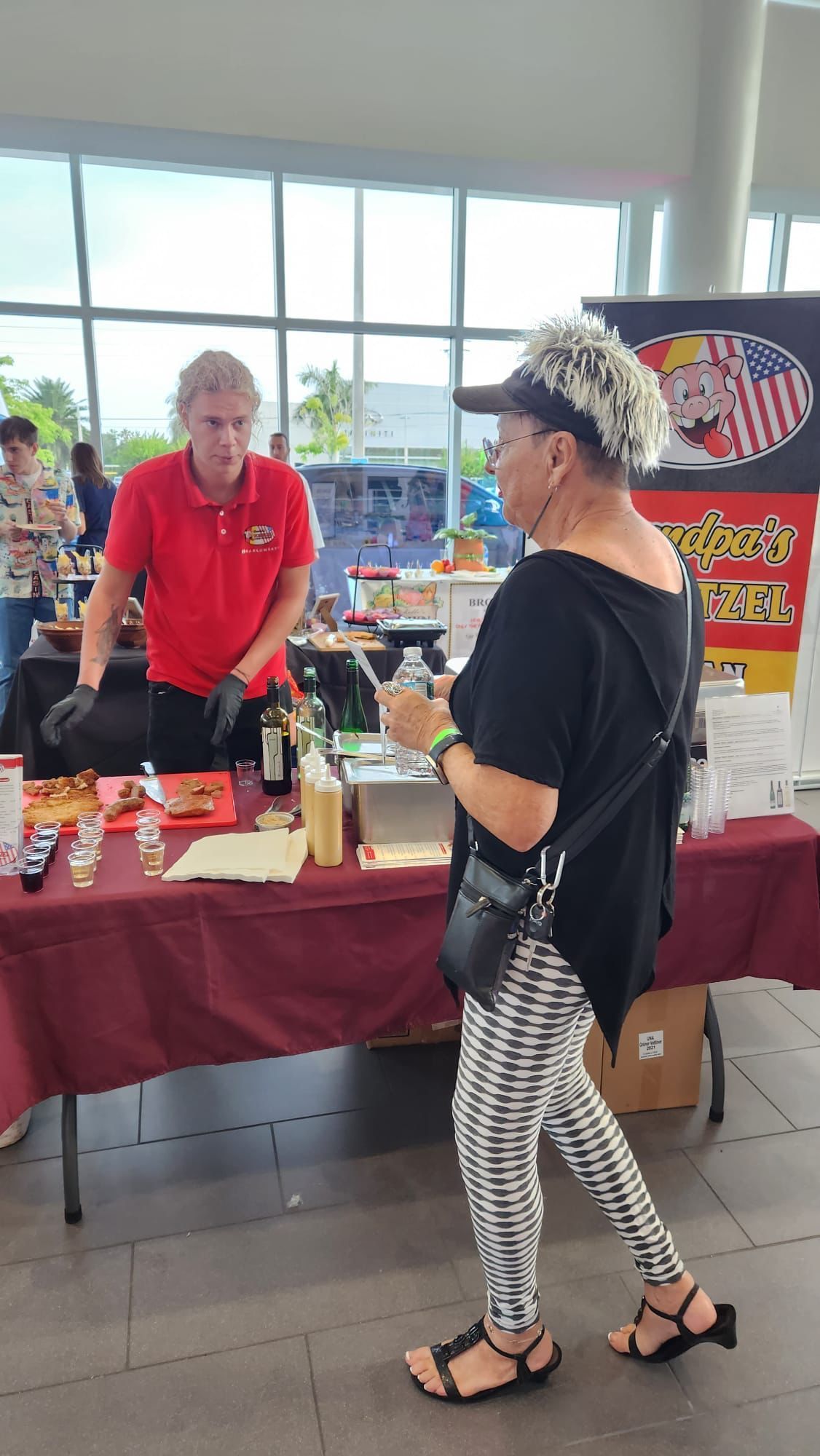 A woman is standing in front of a table with a man standing behind it.