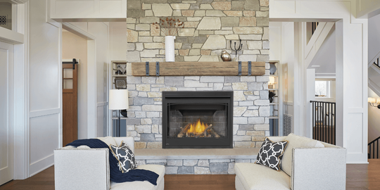 Cozy living room with stone fireplace, lit fire, white armchairs with patterned pillows.