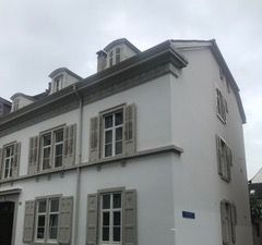 Ein weisses Gebäude mit vielen Fenstern und Fensterläden.