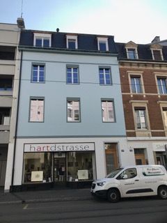 Ein weisser Lieferwagen steht vor einem Gebäude.