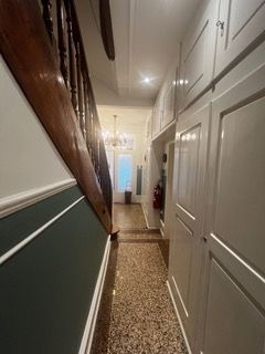 Ein langer Flur mit Treppen und Schränken in einem Haus.