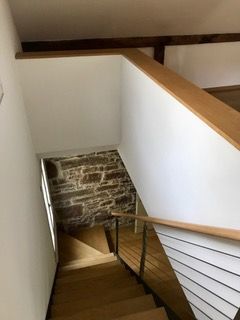 Eine Holztreppe, die zu einer Steinmauer in einem Haus hinaufführt.