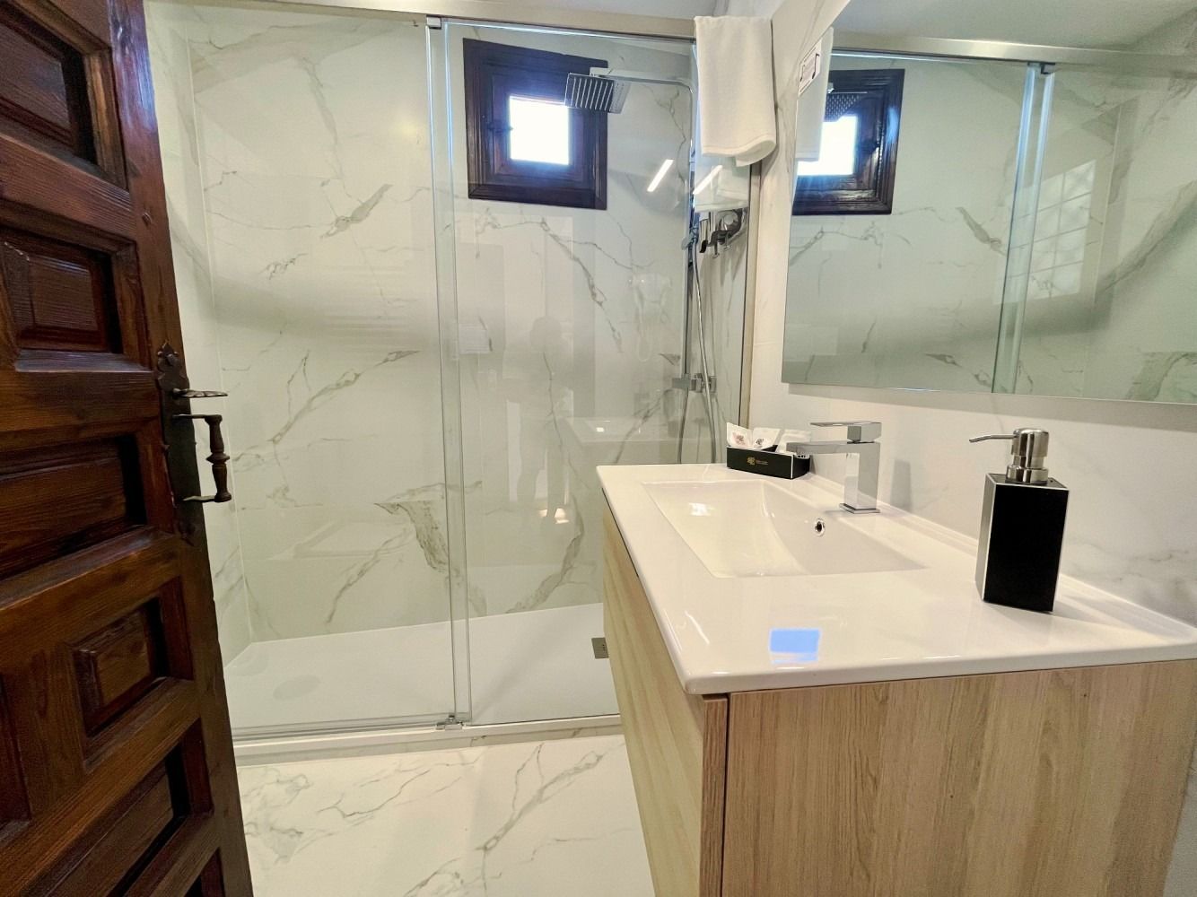 A bathroom with a sink , mirror and shower.