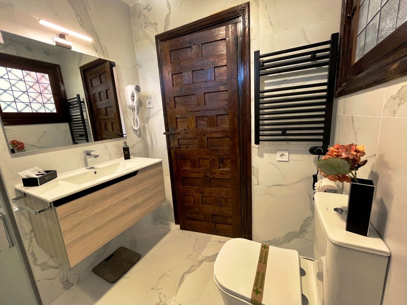 A bathroom with a toilet , sink , mirror and towel rack.