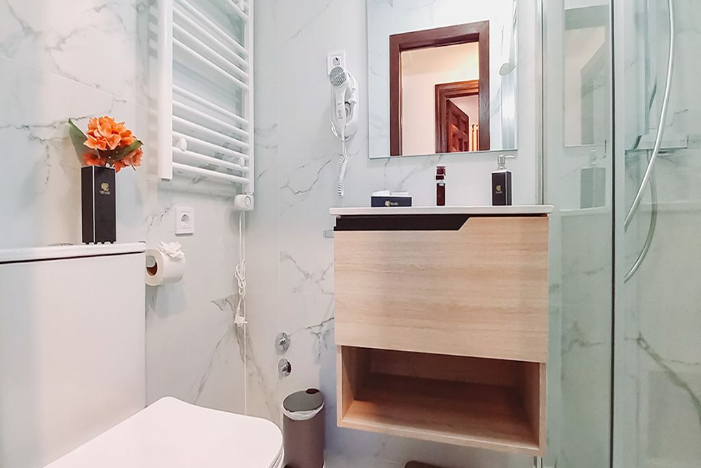 A bathroom with a toilet , sink , mirror and shower.