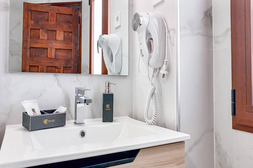 A bathroom with a sink , mirror and hair dryer.