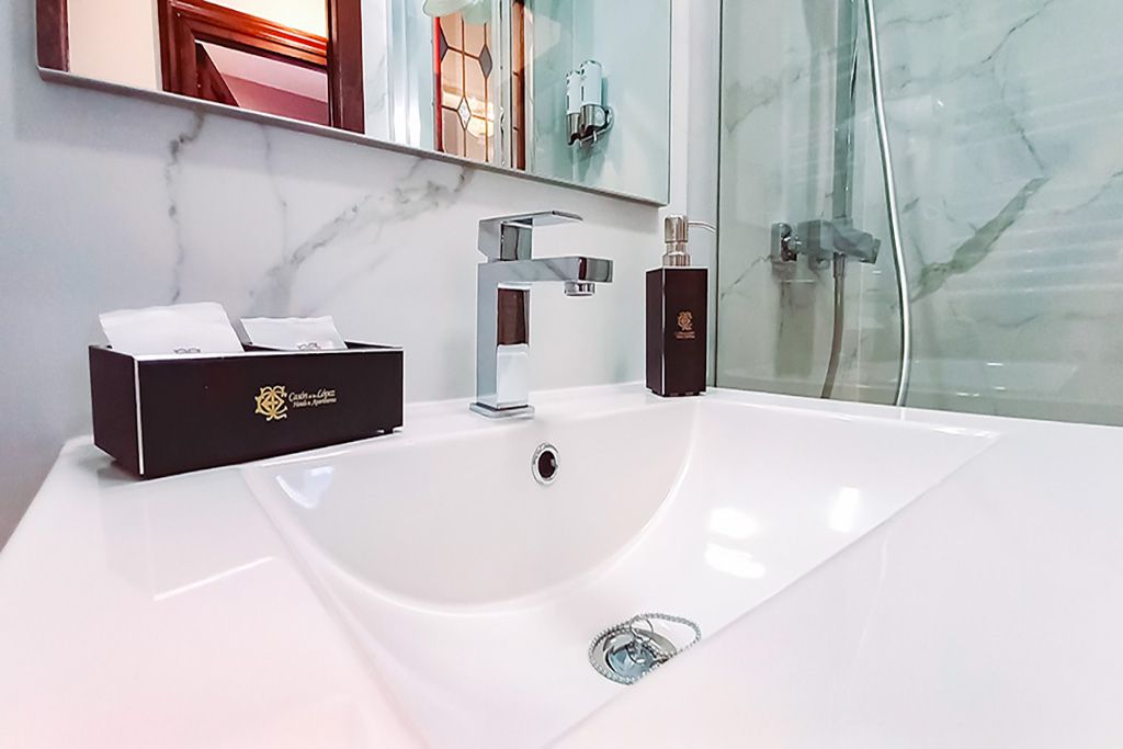 A bathroom with a sink , mirror and shower.