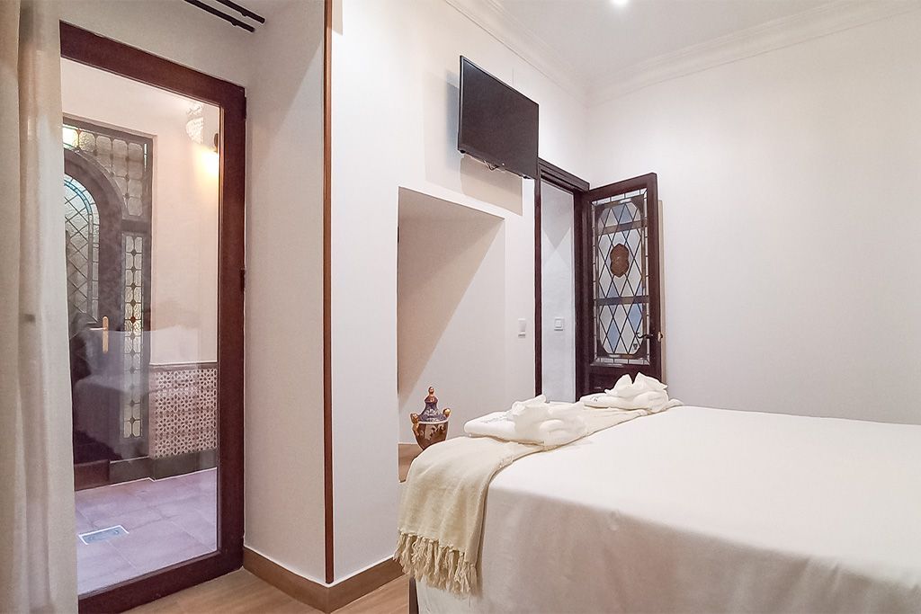 A bedroom with a bed and a television on the wall.