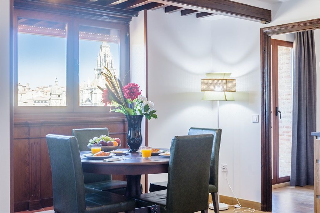 A dining room with a table and chairs and a vase of flowers on the table.