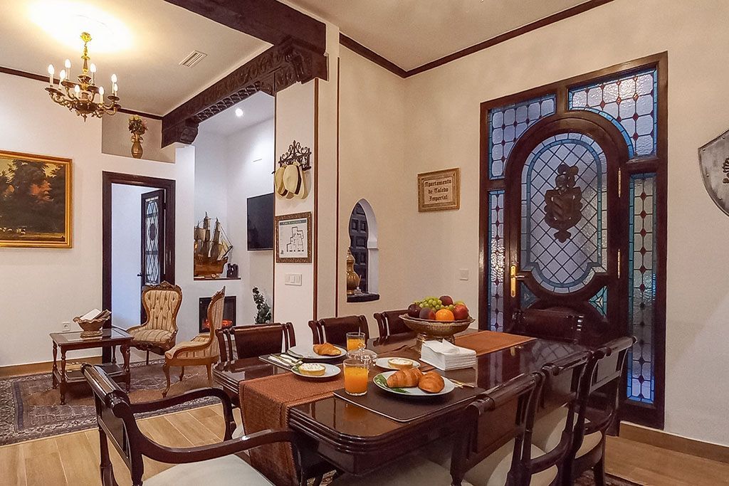 A living room with a dining table and chairs and a clock on the wall.