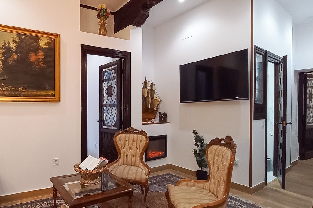 A living room with two chairs , a table , and a flat screen tv.