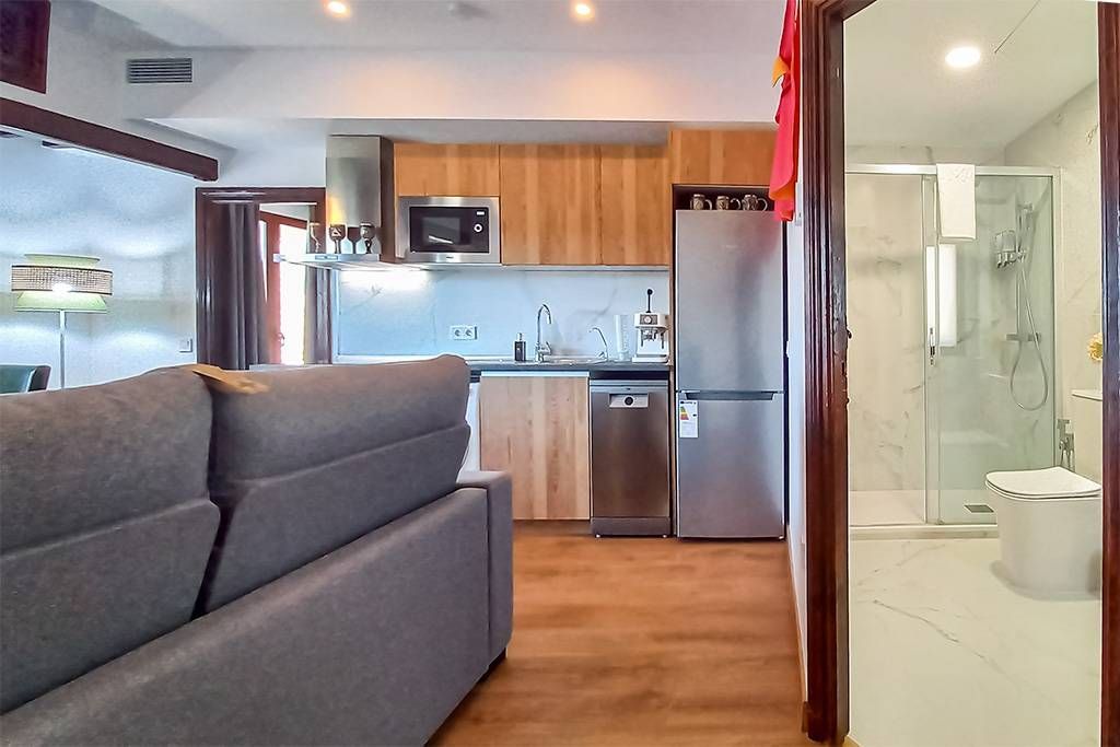 A living room with a couch and a kitchen with stainless steel appliances