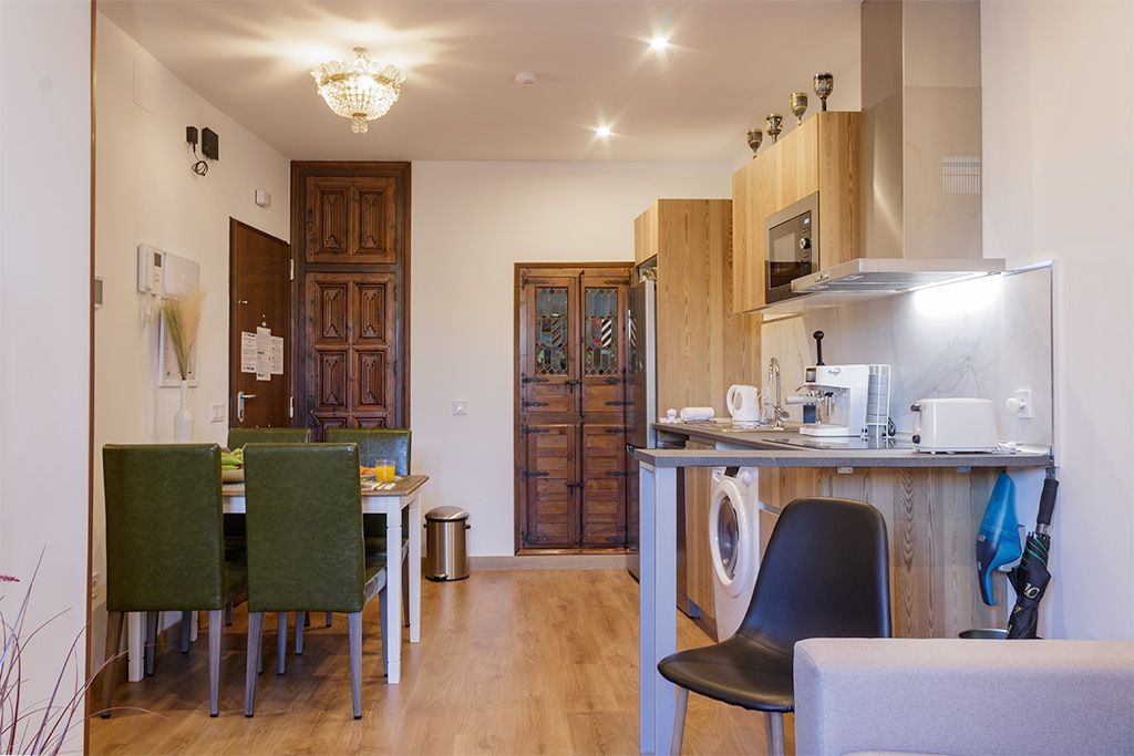 A living room with a dining table and chairs and a kitchen.