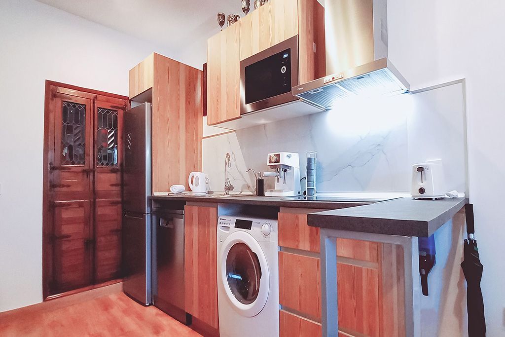 A kitchen with wooden cabinets , a washing machine , a refrigerator , and a microwave.