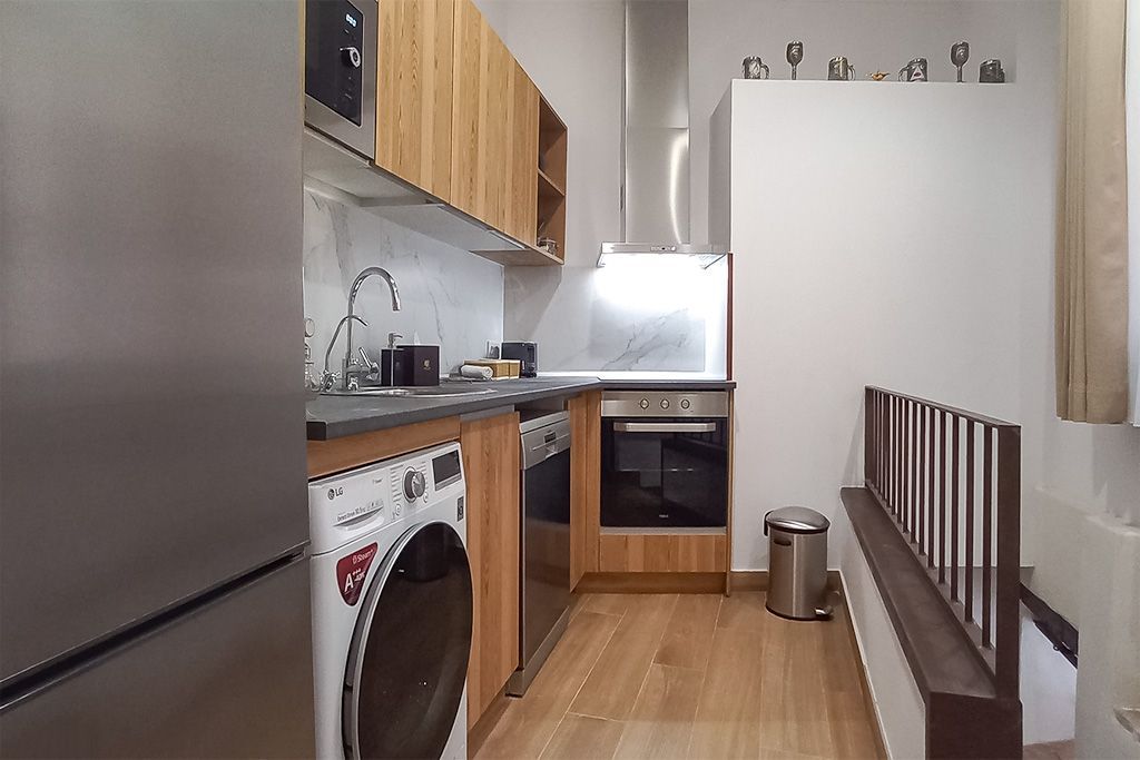 A kitchen with a washing machine and a refrigerator