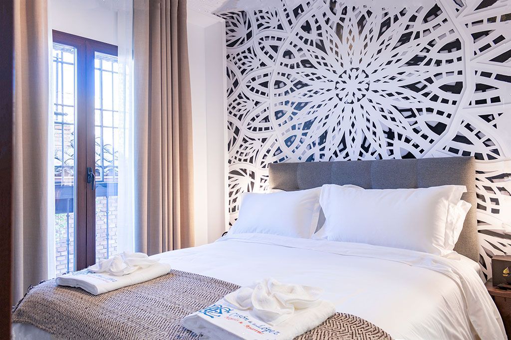 A bedroom with a bed and a window with a mandala on the wall.