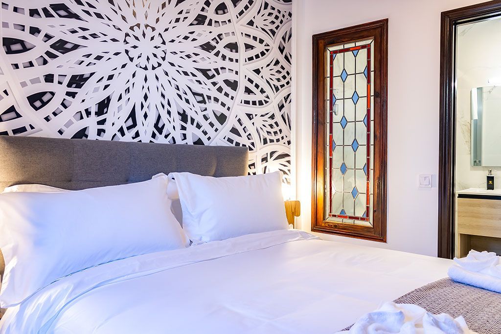 A bedroom with a large bed and a stained glass window.